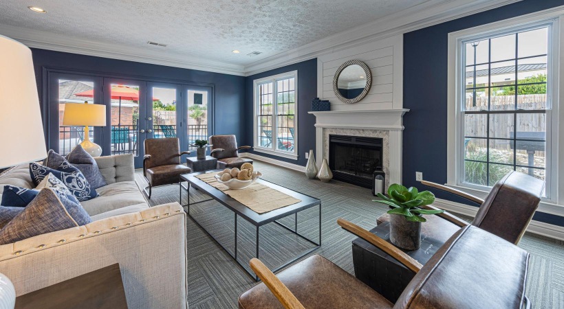 a clubroom with a couch, chairs and a fireplace