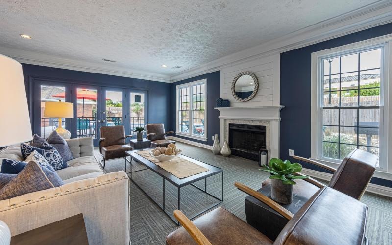 a clubroom with a couch, chairs and a fireplace